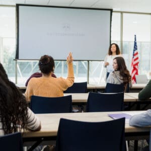 Classroom discussion with a student raising hand.